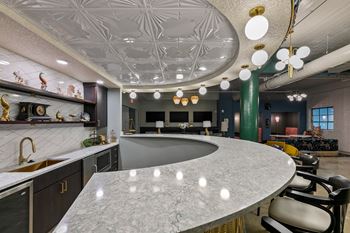 Curved kitchen island with marble countertop and pendant lighting